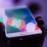 Pessoa segurando smartphone - golpes de clonagem de voz por IA