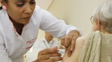 Profissional de saúde aplica vacina em pessoa idosa em unidade de saúde